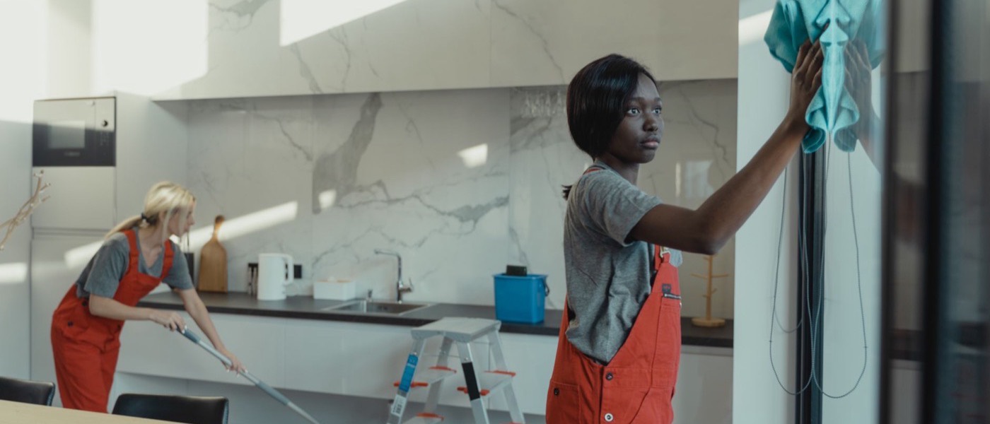 Two commercial cleaners working in a modern kitchen and office space.