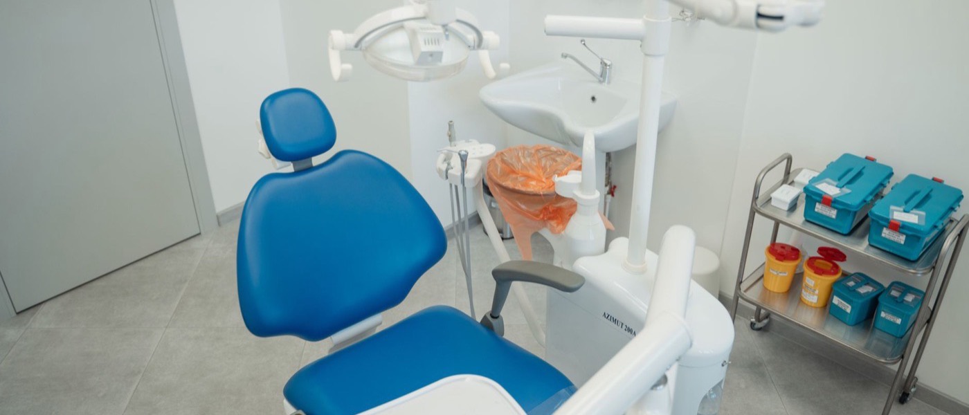 A dental treatment room with a chair and clinical equipment.