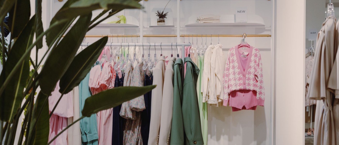 The interior of a small modern clothing boutique with stocked rails.