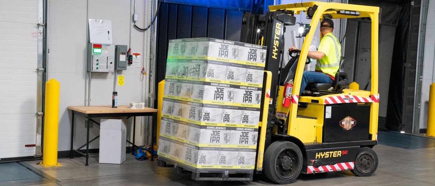 A forklift moving stacked pallets in a distribution warehouse.